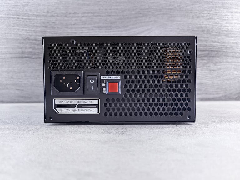Detailed view of a computer power supply unit back panel with power socket, switch, and ventilation grill.