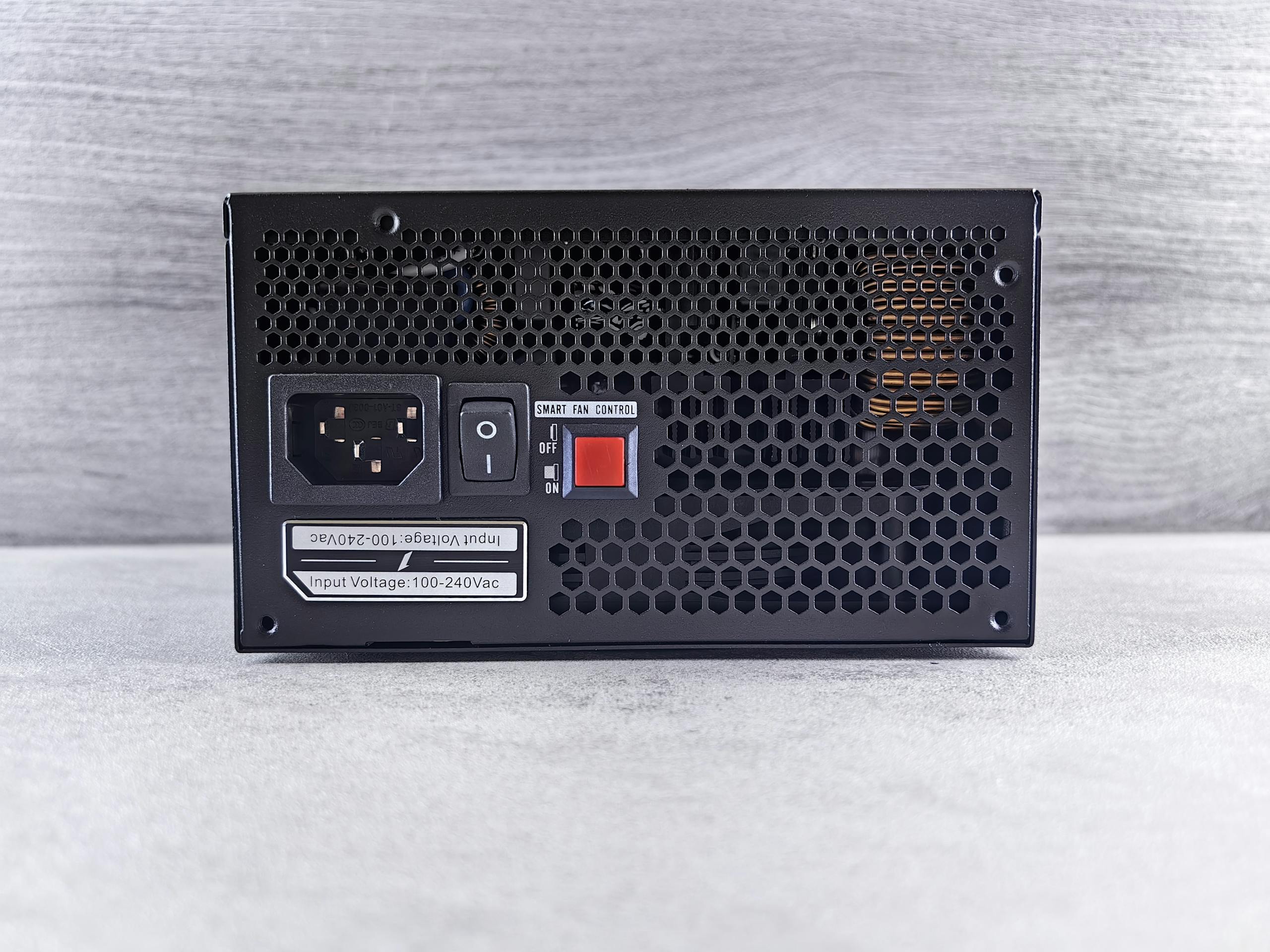 Detailed view of a computer power supply unit back panel with power socket, switch, and ventilation grill.